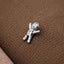 A small silver figurine is sitting on a textured brown surface.
