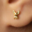 A close-up of a person's ear with a small gold earring featuring a small dog-like figure.