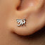 A close-up view of a person's ear adorned with a small silver earring featuring a dragon design.