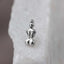 A small silver-colored pendant or charm in the shape of a human figure is displayed against a blurred white background.