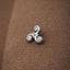 A silver Celtic knot pendant is resting on a textured brown fabric.