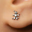 A close-up of a person's ear with a small silver earring featuring a small figure or character attached to it.