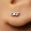 A close-up of a person's ear with a small silver earring in the earlobe.