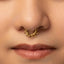 A close-up portrait of a young woman with a gold nose ring, her eyes looking directly at the camera.