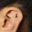 A small silver earring in the shape of a cat is visible in the image.