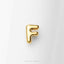 A single, shiny gold letter 'F' is prominently displayed against a white background.