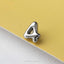 A shiny silver number 4 pin is resting on a yellow surface.