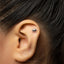 A close-up of a person's ear with a small silver earring in the earlobe.