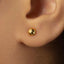 A close-up view of a person's ear with a small gold earring in the earlobe.