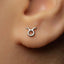 A close-up of a person's ear with a small silver earring featuring a Taurus symbol.