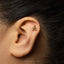 A close-up of a person's ear with a small gold earring in the earlobe.