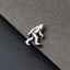 A silver-colored metal object resembling a small, metallic creature or figure is placed on a textured gray surface.