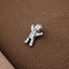 A small silver figurine is sitting on a textured brown surface.