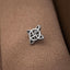 A silver metal pin with a unique, intricate design is resting on a textured fabric surface.