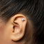 A close-up of a person's ear with a small silver earring in the earlobe.