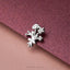 A silver flower brooch is resting on a textured purple surface.