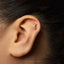 A close-up of a person's ear with a small gold earring in the earlobe.