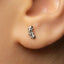 A close-up of a person's ear with a small, silver earring in the earlobe.
