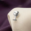 A silver wine glass-shaped cufflink is attached to a beige fabric surface.