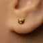 A close-up of a person's ear with a small gold earring featuring a small animal head design.