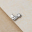 A silver earring in the shape of a cat is resting on a textured surface.
