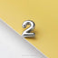 A shiny silver number 2 is placed on a yellow background.