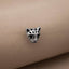 A silver-colored metal charm in the shape of a cat's head is resting on a beige fabric surface.