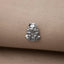 A small silver metal object, resembling a cat or a similar animal, is resting on a beige fabric surface.