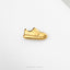 A single gold-colored shoe pin is shown against a white background.