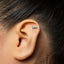 A silver earring with a small shoe-shaped charm is visible in the person's ear.
