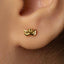 A close-up view of a person's ear with a small gold-colored earring featuring a butterfly design.