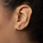 A close-up view of a person's ear adorned with a small, colorful earring featuring a bird design.