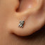 A close-up of a person's ear with a small silver earring featuring a small animal design.