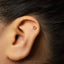 A gold hoop earring is visible in the ear of a person with dark hair.