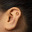 A gold-colored earring with a small circular design is visible in the image.