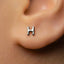 A close-up of a person's ear with a small silver letter 'H' stud earring.