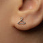 A close-up of a person's ear with a small silver earring in the earlobe.