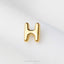 A single, shiny gold letter 'H' is prominently displayed against a white background.