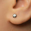 A close-up view of a person's ear with a small silver earring in the earlobe.