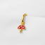A gold-colored mushroom charm with red spots is hanging from a hook against a white background.