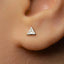 A close-up of a person's ear with a small silver triangle-shaped earring in the earlobe.