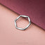 A silver ring with an octagonal shape is resting on a pinkish-red background.
