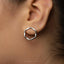 A close-up view of a person's ear wearing a silver hexagonal earring.