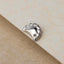 A silver earring is resting on a textured surface.