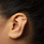 A close-up of a person's ear with a small gold-colored earring inserted into the earlobe.