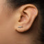 A close-up of a person's ear with a small silver earring in the earlobe.