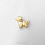 A small golden dog-shaped pin is placed on a white surface.