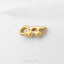 A gold-colored earring with the word "OFF" engraved on it, resting on a white surface.