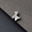 A small silver metal object resembling a dog or a similar animal shape is resting on a textured gray surface.
