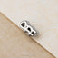 A small silver key-shaped charm is resting on a textured surface.